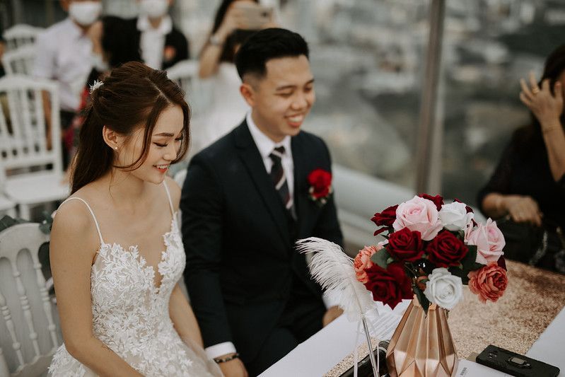 A romantic outdoor wedding ceremony setup with floral arrangements and white draping against a cloudy sky.