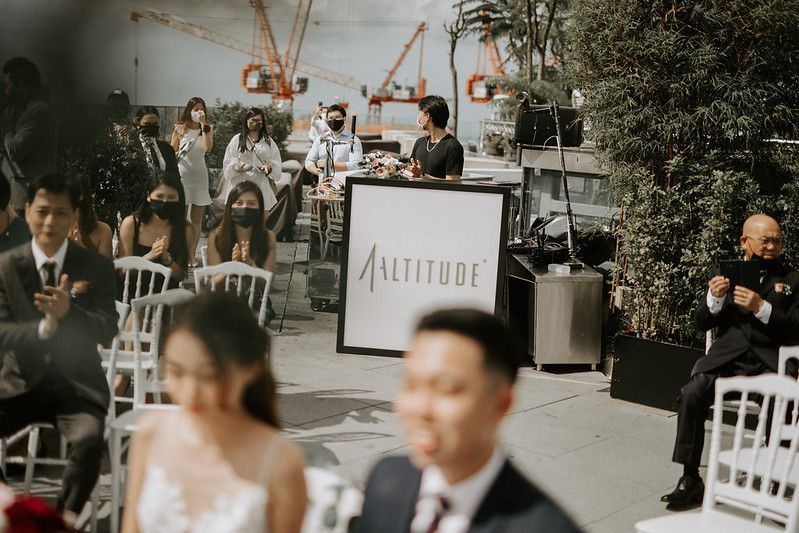 Modern outdoor wedding ceremony setup with white chairs and floral decorations on a rooftop venue.