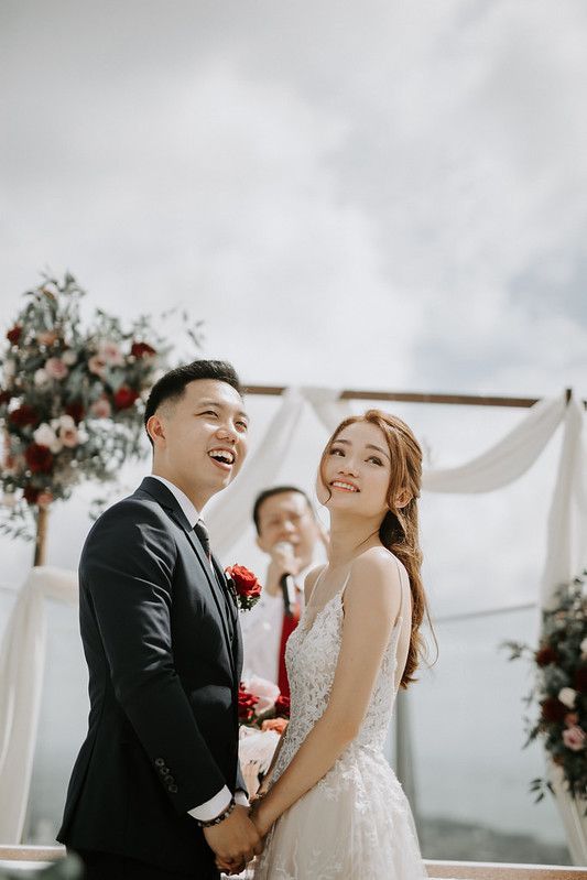 Joyful wedding ceremony moments captured under a white floral arch on a rooftop venue.