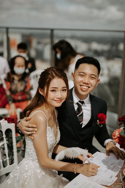 Couple sharing happy moments during their rooftop wedding ceremony while signing documents.