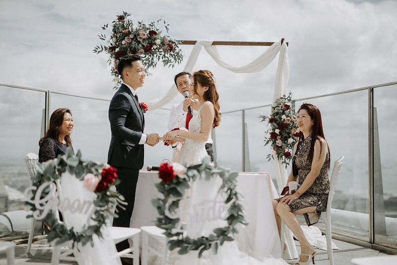 Modern rooftop wedding setup with white draping and floral arrangements against city views.