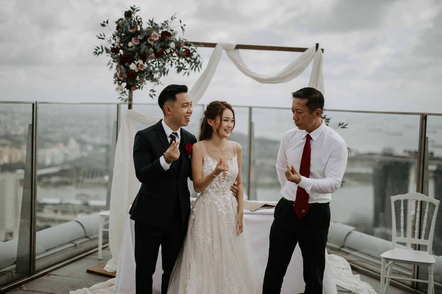 Wedding ceremony decor featuring white draping and floral arrangements on an urban rooftop.