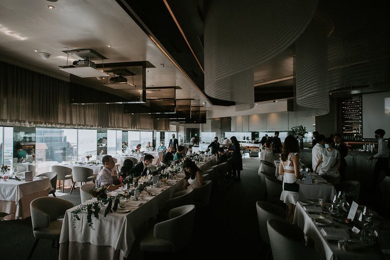 Modern wedding venue interior with industrial style ceiling and elegant white drapery decorations.