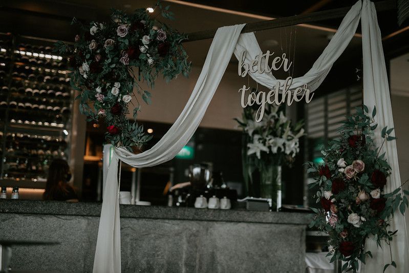 Wedding reception hall setup with tables and chairs arranged under elegant lighting.
