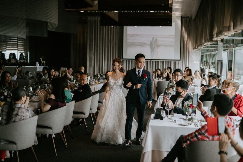 Wedding celebration with guests seated at decorated tables in a modern venue.