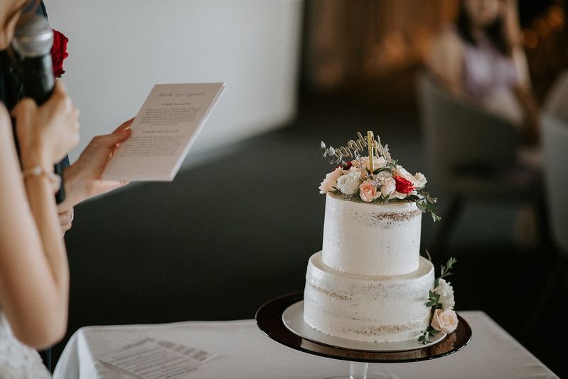Close-up of minimalist white wedding cake with delicate floral accents.