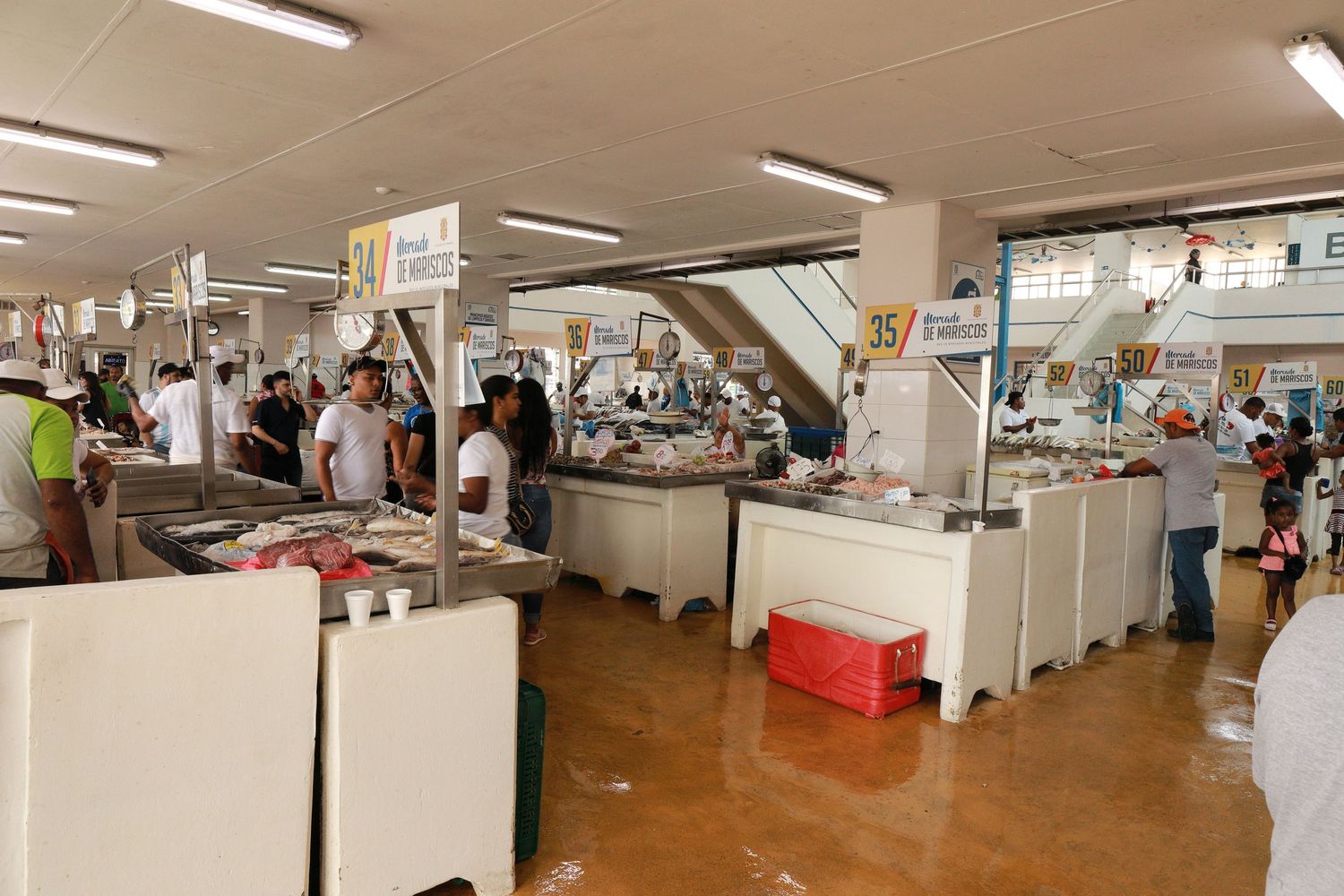 Wide view of an indoor market hall with multiple vendor stalls and shoppers.