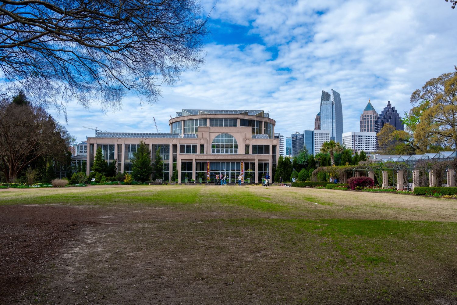 Modern building with Atlanta skyline visible in background under cloudy blue sky.