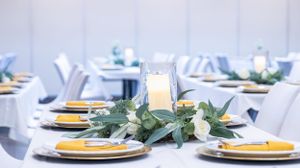 Wedding table decorated with white flowers, greenery, and gold charger plates.