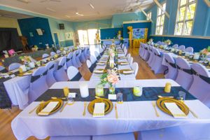 Elegant wedding reception hall with tables set in purple and gold decor.