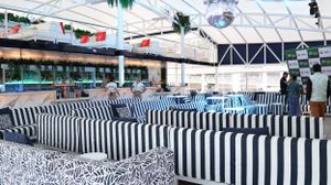 A modern event space with black and white striped seating under a glass ceiling.