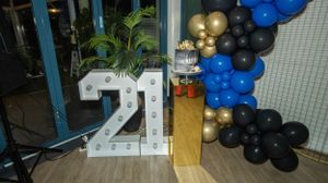 White LED number 21 sign with tropical plants and balloon arrangements.