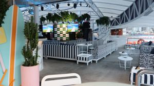 An empty event space with modern AV equipment, striped barriers and tropical plants.