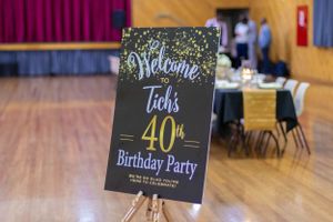 Welcome sign for a 40th birthday party displayed on an easel in a wooden floored venue.
