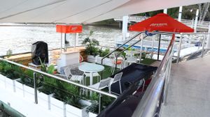 An outdoor deck area with lounge furniture and red umbrellas overlooking water.