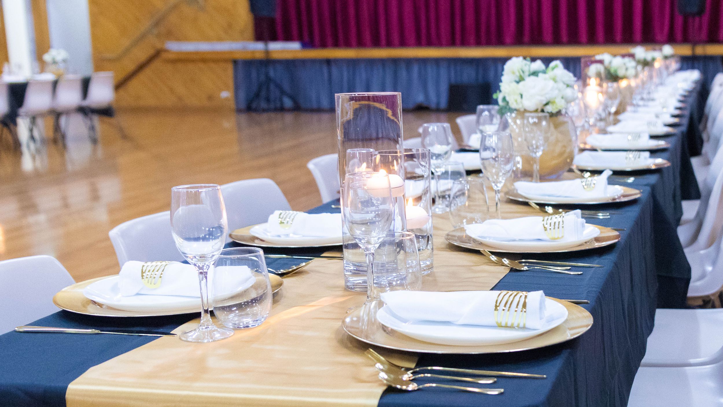 Formal dining setup with navy tablecloths and white place settings in a banquet hall.