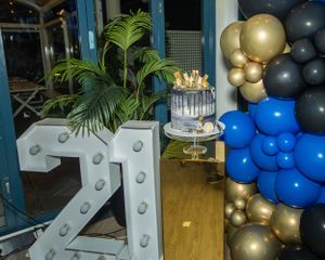 Large illuminated number 21 display with balloon decorations in gold and blue.