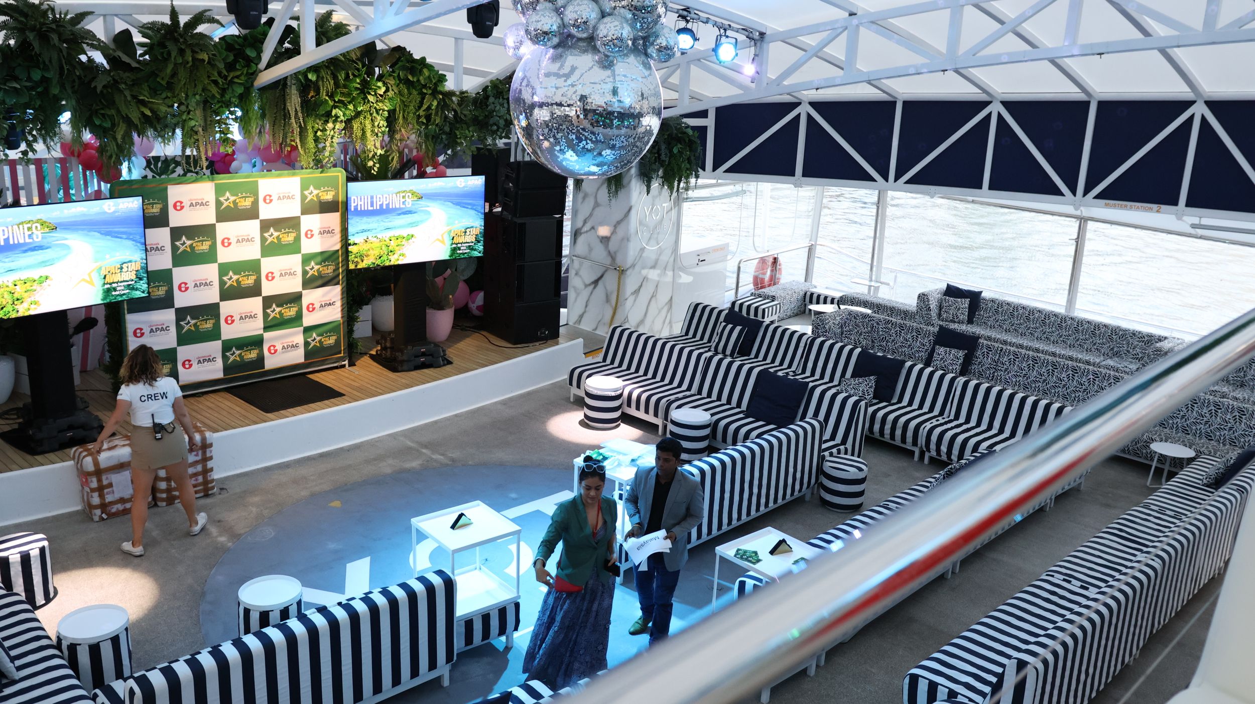 A stylish event venue with black and white decor and tropical plant elements.