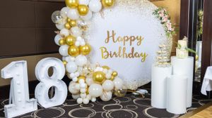 Elegant birthday party decoration with 18 numbers and gold and white balloon arch display.