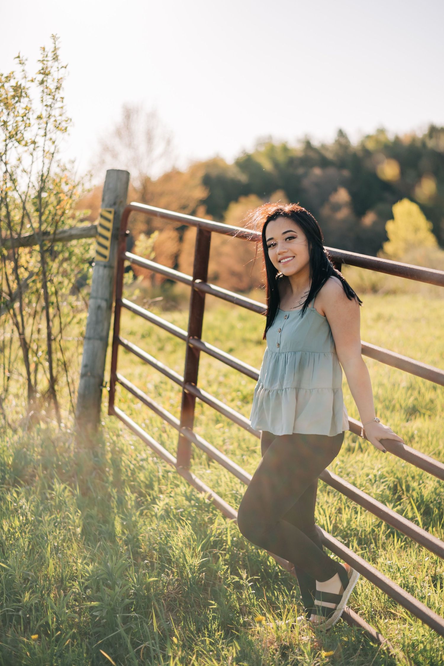 high school senior leaning against a fence gate
