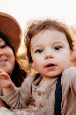 Close-up portrait of young child in beige top during golden hour.