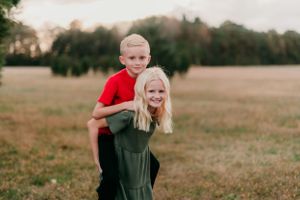 Two children play together in a field during golden hour.