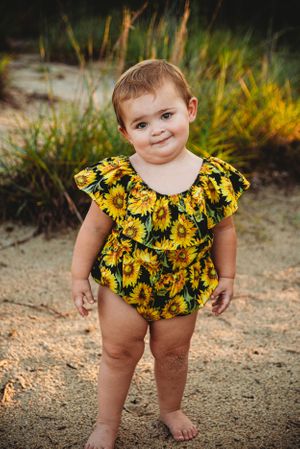 A adorable sunflower-patterned romper on display in an outdoor garden setting.