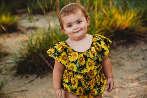 A delightful yellow sunflower romper captured in a natural outdoor setting.
