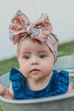 Baby wearing a floral bow headband and navy blue ruffled dress.