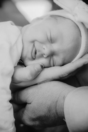 Peaceful newborn baby sleeping soundly wrapped in white blanket.