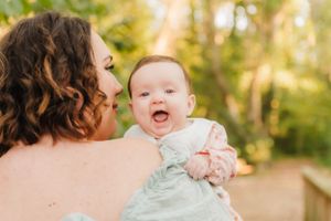 Sweet candid moment between parent and laughing baby in outdoor setting.