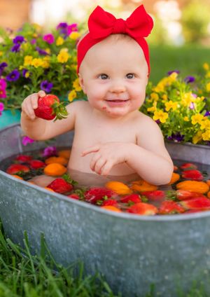 A delightful bath time scene in a galvanized tub filled with citrus fruits and strawberries, surrounded by colorful flowers.