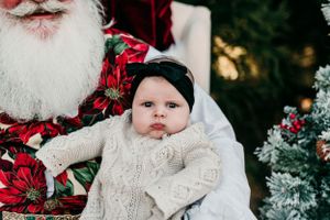 Holiday portrait with Santa showing baby in white knit dress.