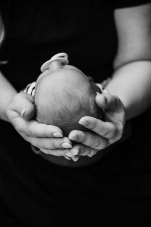 Black and white image of gentle hands cradling a newborn baby.