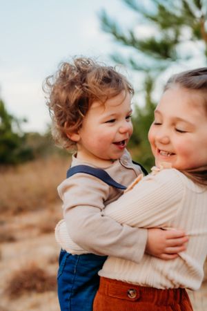 Candid moment of children sharing laughter outdoors during sunset.
