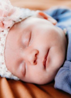 Peaceful sleeping baby in lace outfit captured in dreamy closeup portrait.
