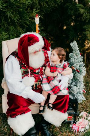 Classic holiday portrait with Santa in traditional red suit and decorated Christmas setting.