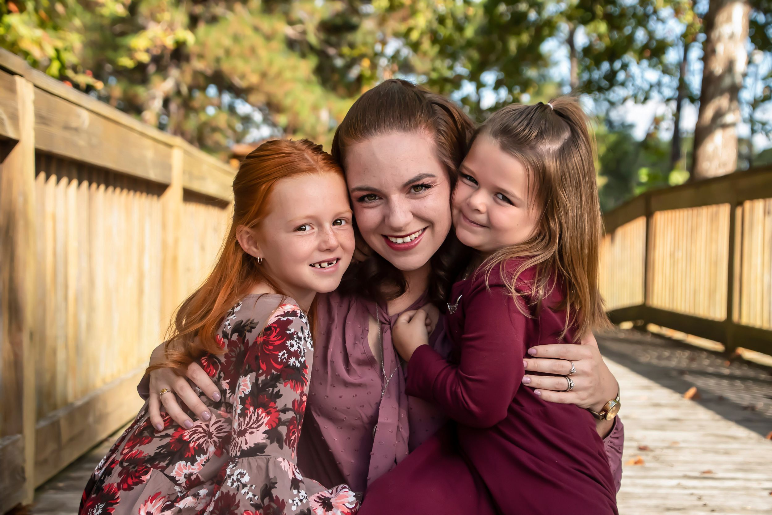 Joyful outdoor family portrait on wooden deck with warm natural lighting.