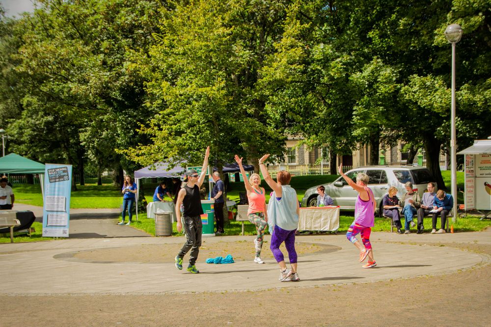 People exercising together in a park during outdoor fitness class.