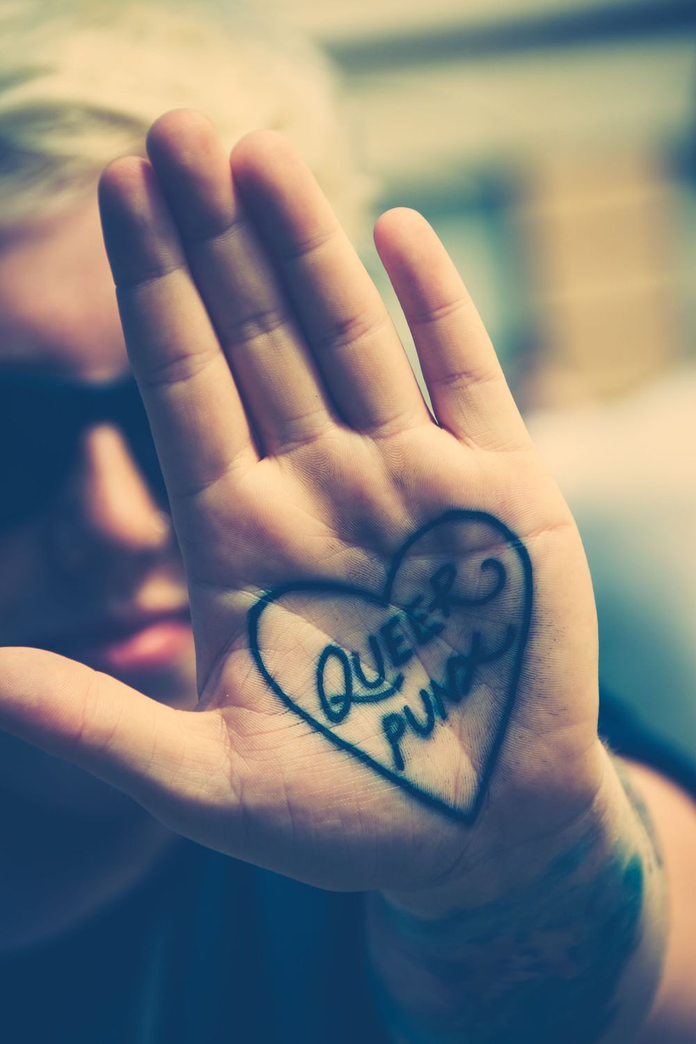 The word 'Love' written in cursive across an open palm against a soft blurred background.