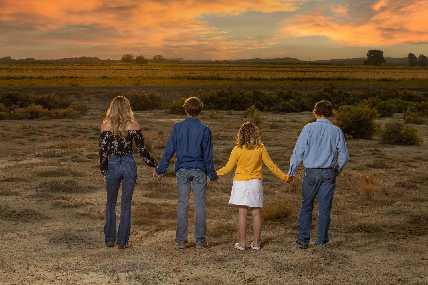 Family silhouetted against vibrant sunset sky in desert landscape.