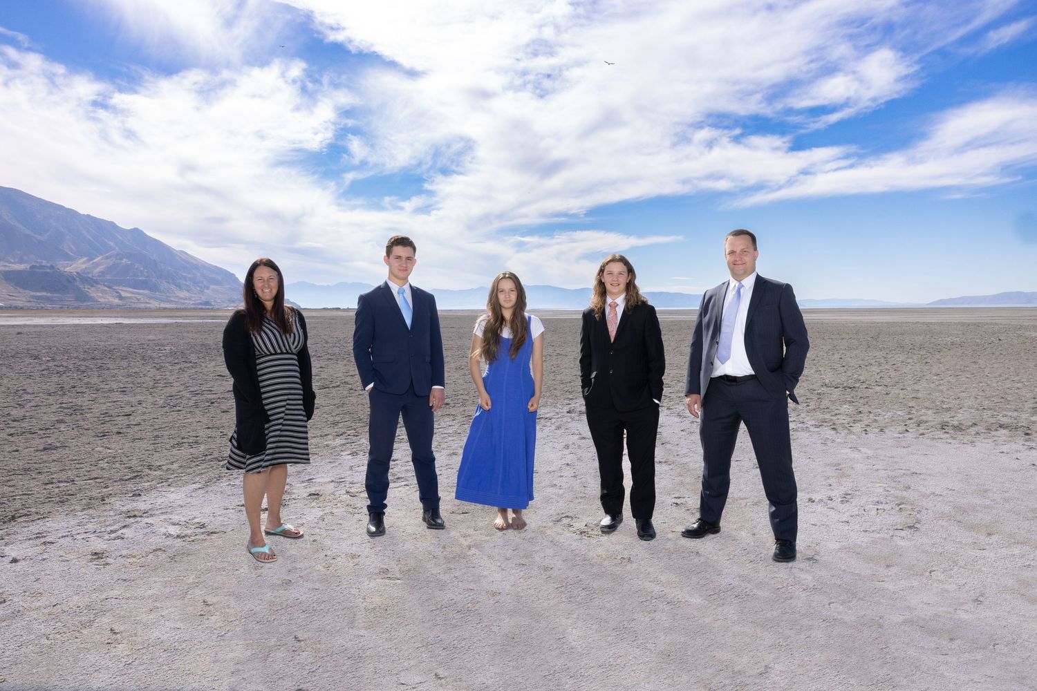 Professional group standing together on salt flats with mountains and blue sky in background.