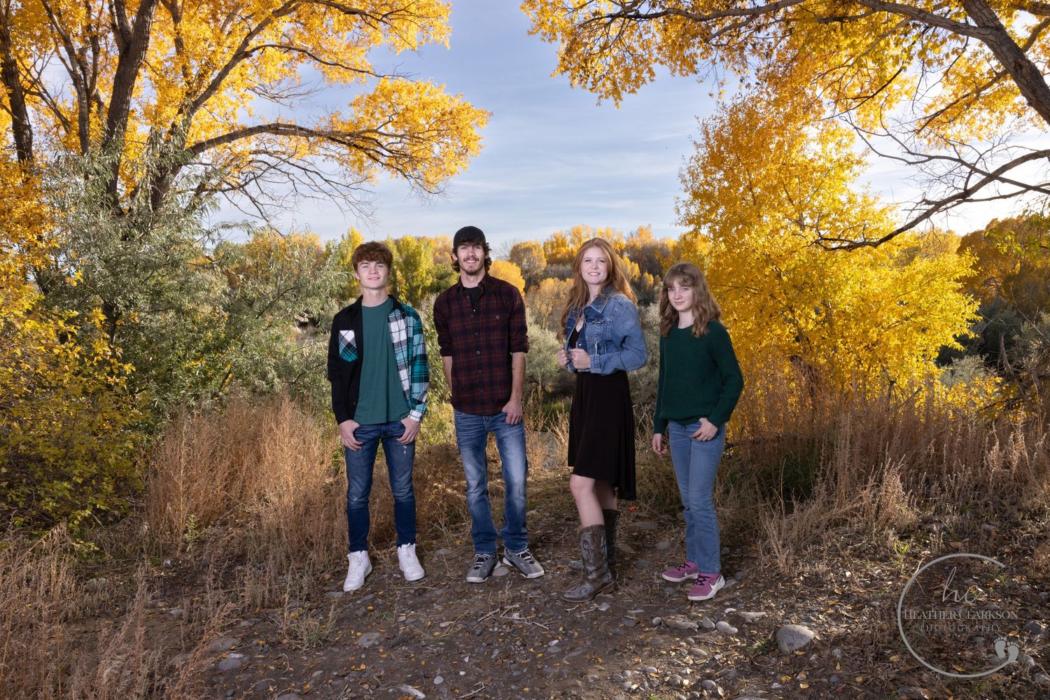 Small group standing together on autumn trail with golden trees in background.