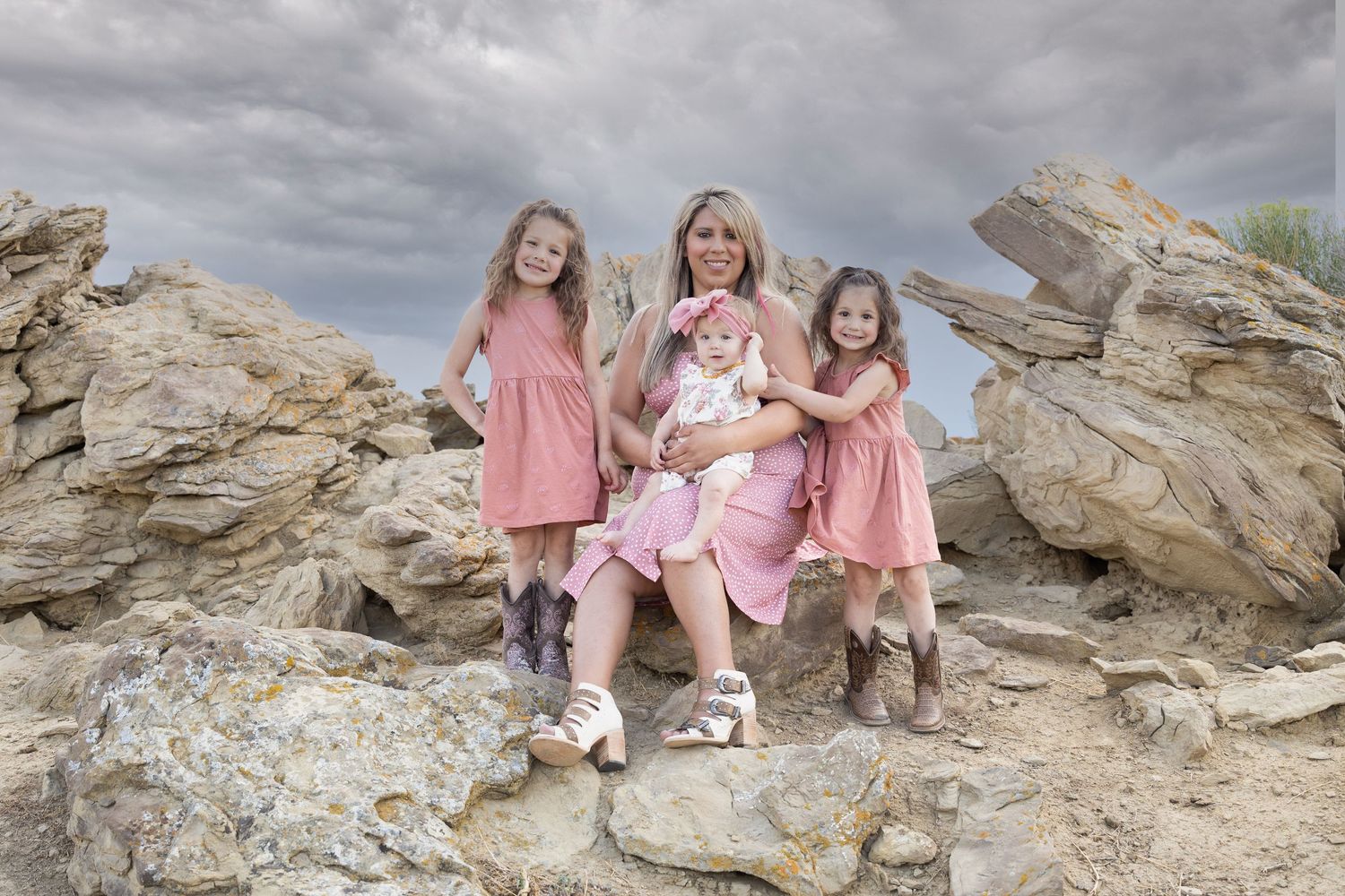 Family members in coordinating pink outfits pose on rocky landscape.