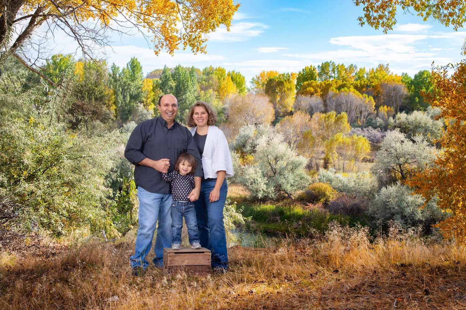 Beautiful autumn landscape with yellow trees provides backdrop for casual family portraits.
