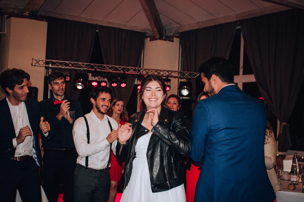 Wedding reception party scene with guests dancing under wooden beamed ceiling.