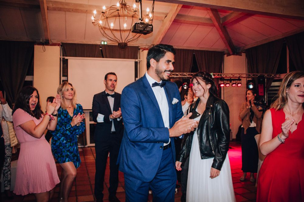 Newlyweds dancing at their wedding reception while guests celebrate in the background.