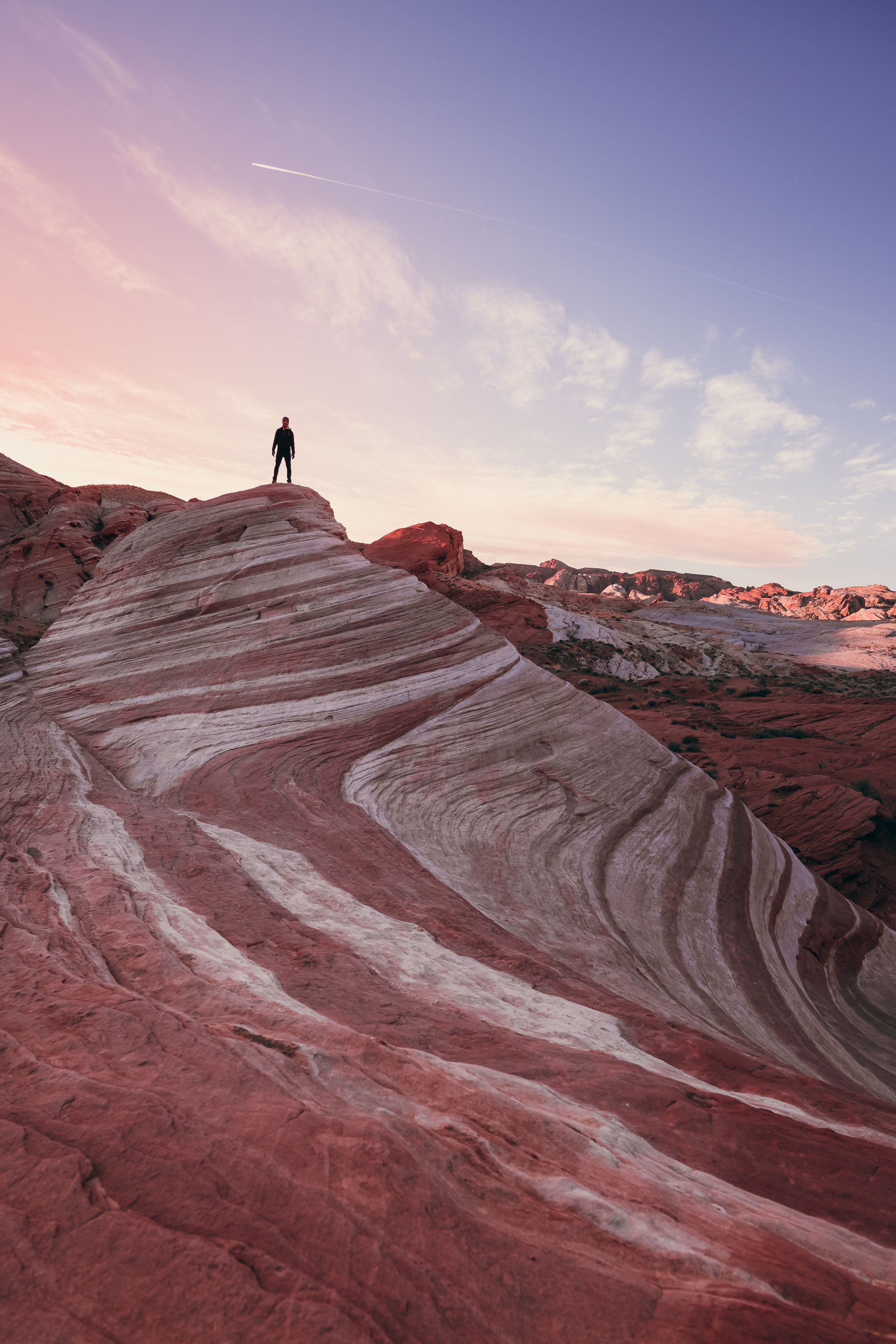 Man standing on top of the Fire Wave during sunrise in Valley of Fire State Park in Nevada.