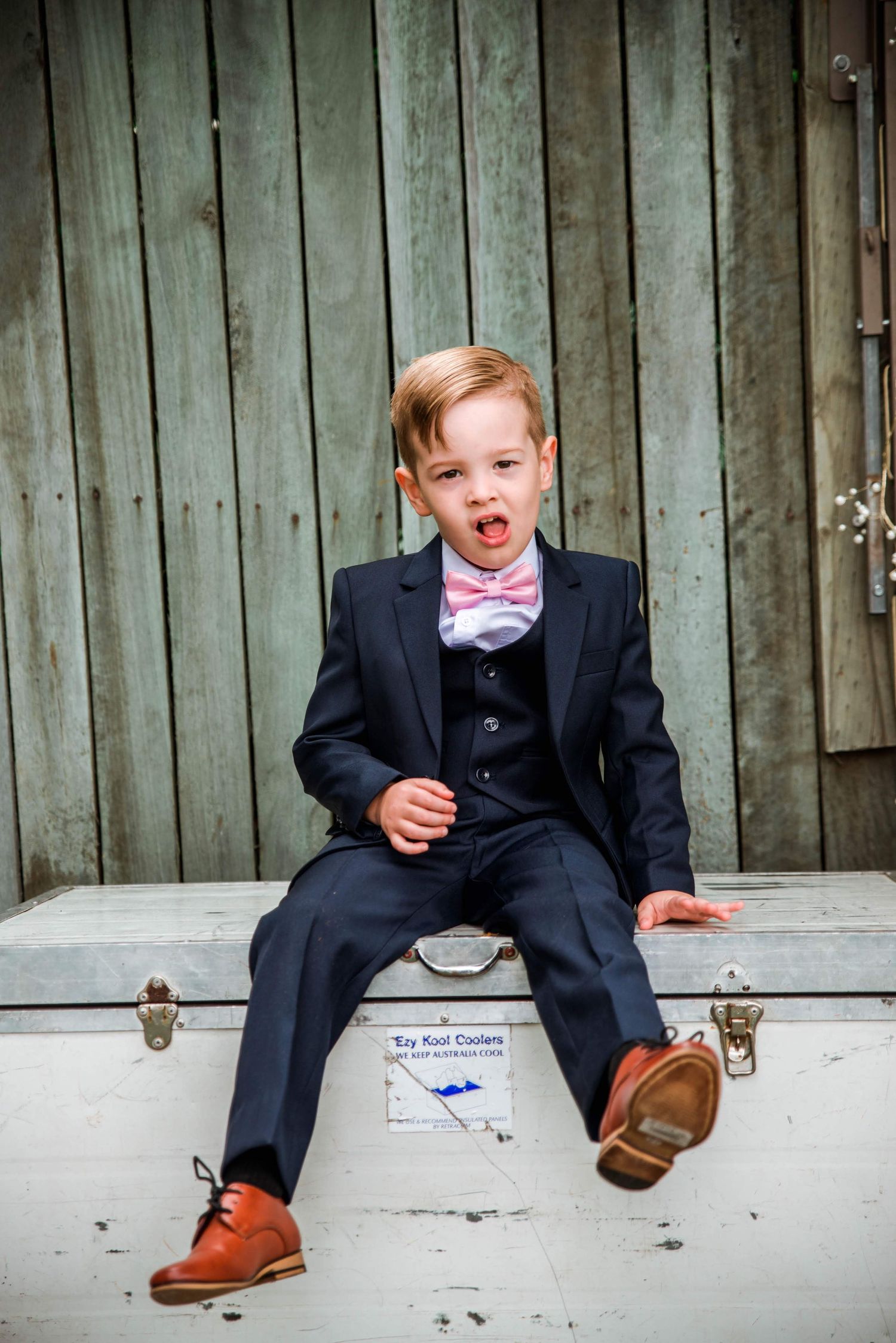 An expressive moment captured of a young wedding attendee in formal attire.