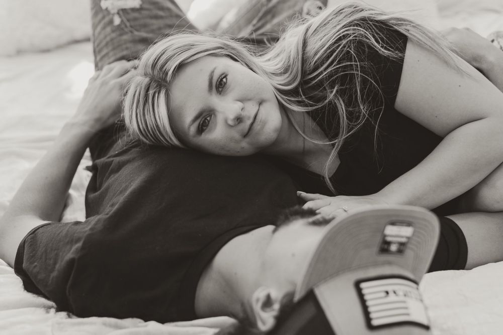 Intimate lifestyle photos of couple lying together during romantic indoor shoot.